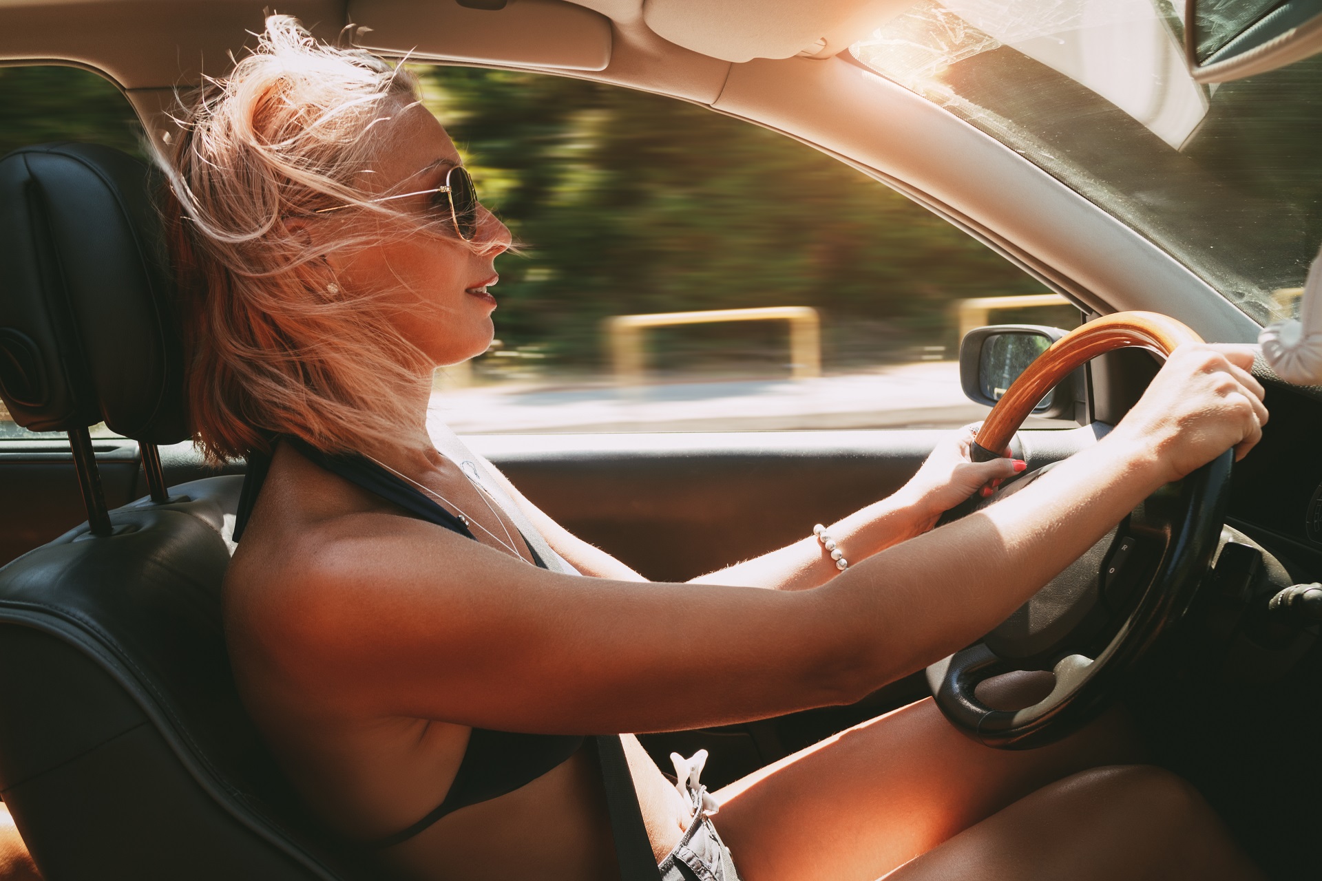 Young beautiful smiling girl in bikini driving a car.